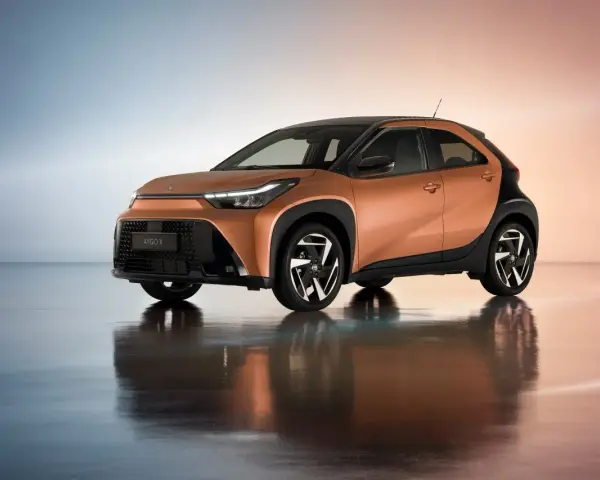 Pomarańczowa Toyota Aygo X z czarnymi dodatkami, idealna do miasta. Sprawdź atrakcyjną toyota hybryda cena.