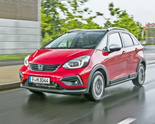 Czerwony Honda Jazz 4 w wersji Crosstar z czarnym dachem i relingami, porusza się po mokrej drodze.