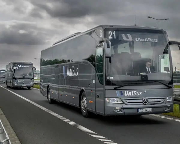 Szary bus UniBus z numerem 21 jedzie autostradą. To jeden z wielu pojazdów na trasie Kraków-Katowice.