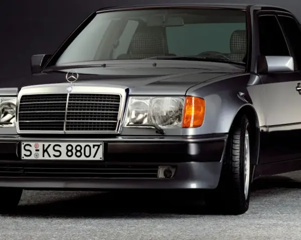 Klasyczny youngtimer, szary Mercedes-Benz W124 z charakterystyczną kratką i reflektorami.