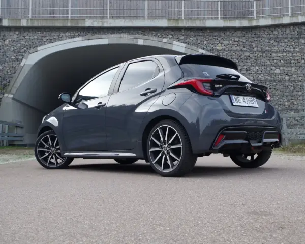 Szary Toyota Yaris Hybrid stoi przed tunelem. Dowiedz się, ile pali Toyota Yaris Hybrid, analizując jego osiągi.