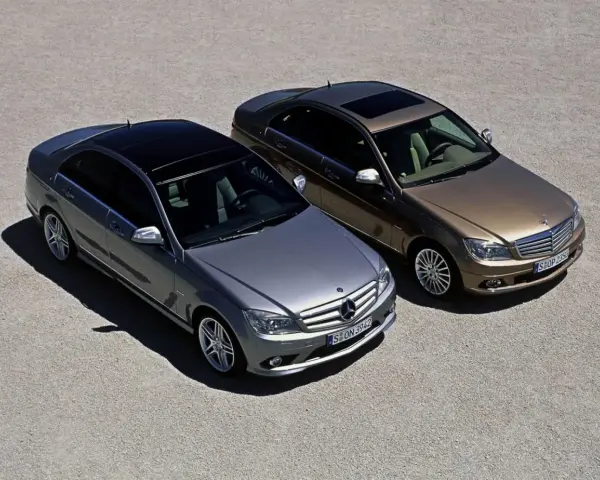 Dwa Mercedesy klasy C W204, jeden srebrny, drugi brązowy, stoją obok siebie na żwirowym placu.