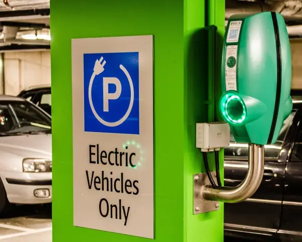 Znak "Tylko pojazdy elektryczne" i zielona ładowarka EVbox. Zastanawiasz się, ile kosztuje ładowanie samochodu elektrycznego w domu?