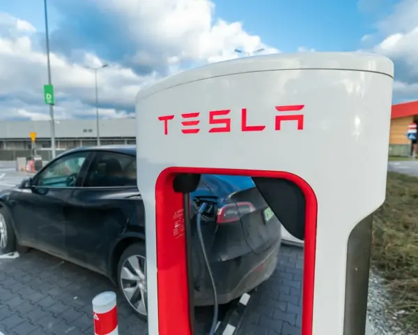 Czarna Tesla podłączona do ładowarki. Zastanawiasz się, ile kosztuje ładowanie Tesli? To zależy od taryfy i lokalizacji.