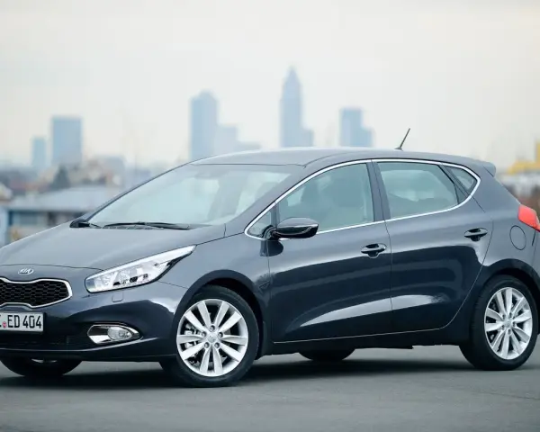 Ciemnoszary Kia Ceed 1. hatchback stoi na tle miejskiej panoramy.