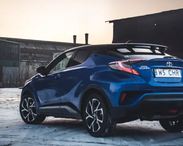 Niebieska Toyota C-HR Hybrid na tle opuszczonych budynków. Czy wybrać hybrydę czy benzynę?