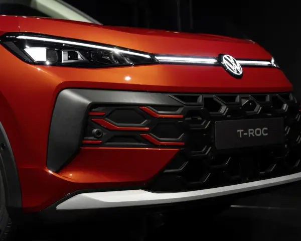Nowy VW T-Roc w kolorze pomarańczowym prezentuje się z przodu z charakterystycznym grillem i nowoczesnymi światłami IQ.LIGHT.