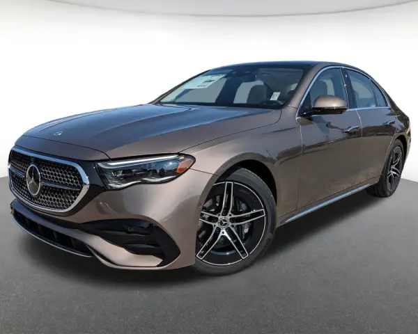 Elegancki brązowy Mercedes-Benz E450 sedan z czarnymi felgami stoi na szarym podłożu.
