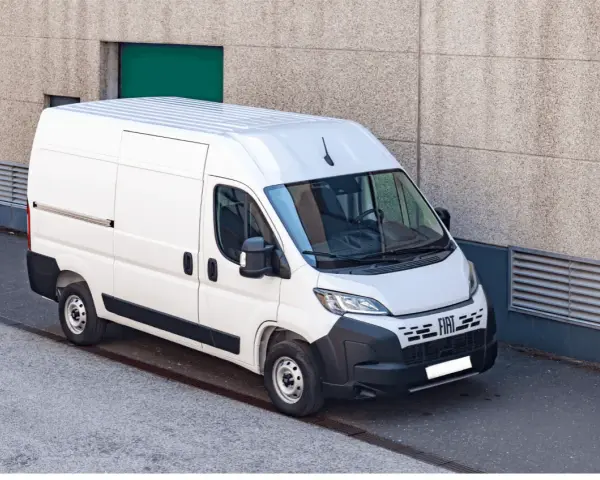 Biały bus 9 osobowy Fiat Ducato, zaparkowany przy betonowej ścianie. Zastanawiasz się, ile pali bus 9 osobowy?
