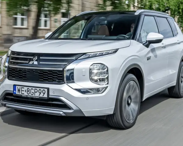 Biały Mitsubishi Outlander PHEV, jeden z nowoczesnych modeli tej marki, jedzie po mieście.