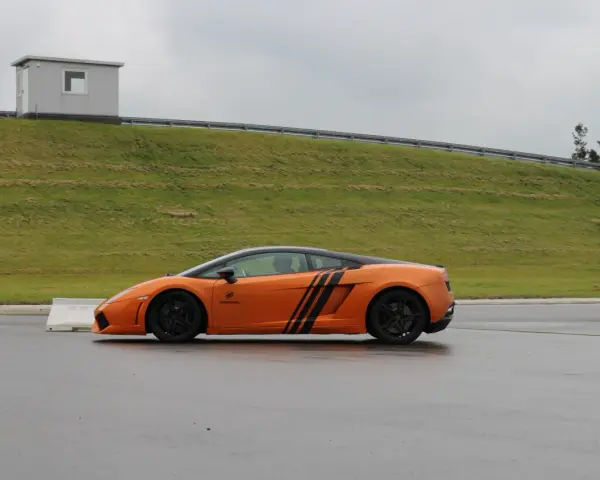 Pomarańczowe Lamborghini na torze. Zastanawiasz się, ile kosztuje przejazd takim autem?