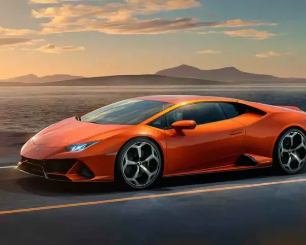 Pomarańczowy Lamborghini Huracan pędzi po pustej drodze nad jeziorem o zachodzie słońca.