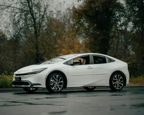 Biała Toyota Prius na mokrej drodze. Zastanawiasz się, ile wytrzymuje bateria w hybrydzie Toyoty?