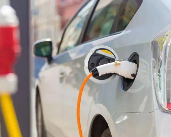 Samochód elektryczny podłączony do ładowarki. Zastanawiasz się, co ile trzeba ładować samochód elektryczny? To zależy od wielu czynników, ale zazwyczaj raz na kilka dni.
