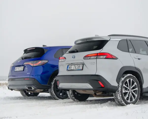 Porównanie hybryd: niebieska Honda CR-V e:HEV i srebrna Toyota Corolla Cross Hybrid AWD na śniegu. Którą wybrać?