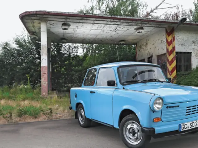 Niebieski trabant stoi przed opuszczoną stacją benzynową.