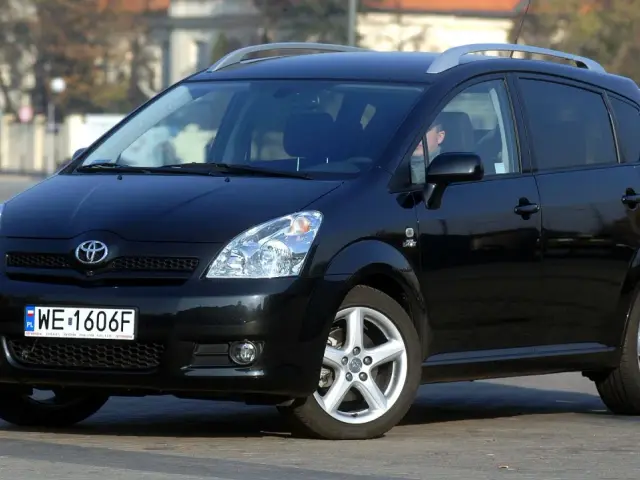 Czarna Toyota Corolla Verso z relingami dachowymi, zaparkowana na ulicy.