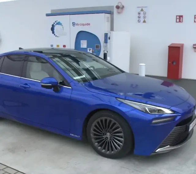 Niebieska Toyota Mirai na stacji wodorowej. Zastanawiasz się nad toyota mirai cena?