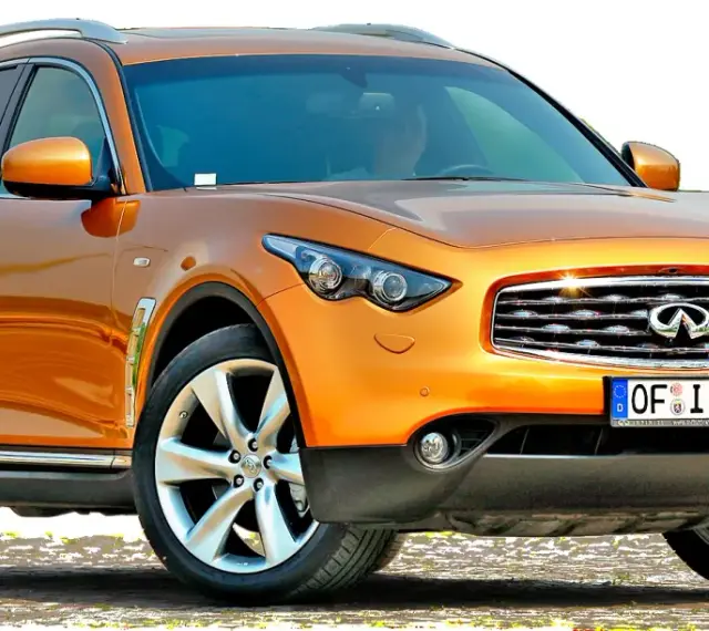 Pomarańczowy infiniti samochód z chromowanymi detalami i felgami, gotowy na przygodę.