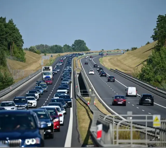 Korek na autostradzie bursztynowej. Długi sznur samochodów i ciężarówek sunie powoli w upalny dzień.