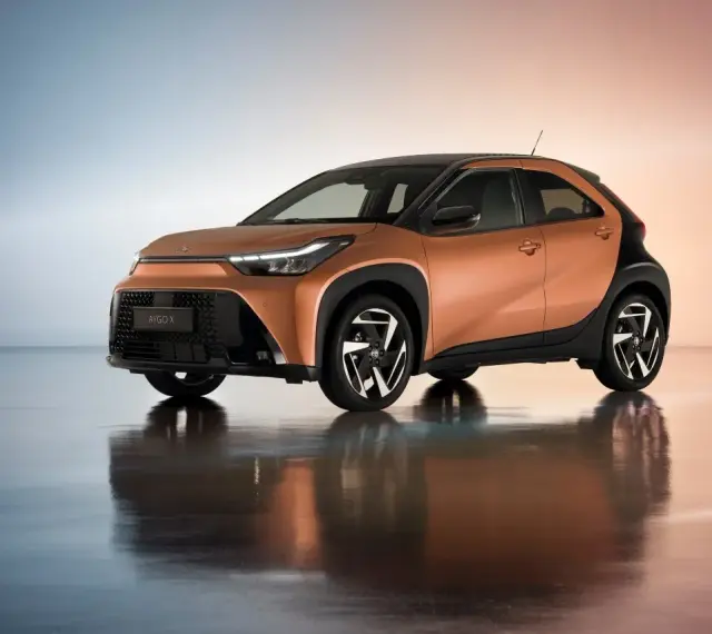 Pomarańczowa Toyota Aygo X z czarnymi dodatkami, idealna do miasta. Sprawdź atrakcyjną toyota hybryda cena.