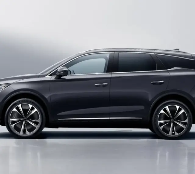 Ciemnoszary BYD Tang, SUV z eleganckimi felgami, prezentuje się na tle jasnej ściany. Sprawdź byd tang cena i jego możliwości.
