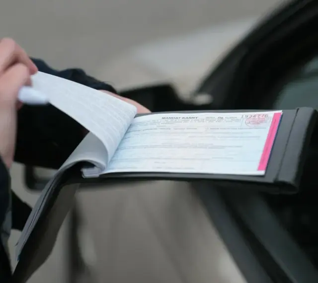 Policjant wypisuje mandat za kolizję. Dokument zawiera numer seryjny i pieczęć.