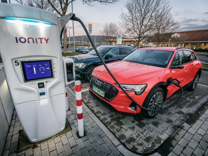 Na stacji Ionity czerwony Audi e-tron ładuje się. Ekran pokazuje 91% naładowania i 77kW mocy. Ile trwa ładowanie samochodu elektrycznego na stacji?