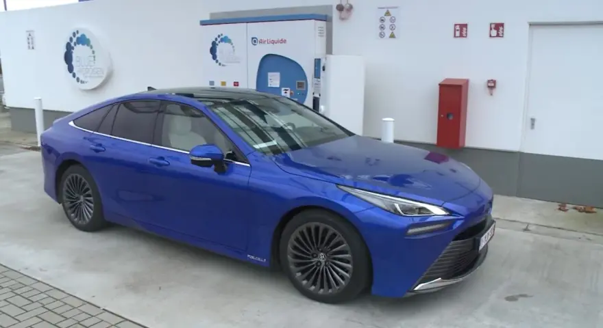 Niebieska Toyota Mirai na stacji wodorowej. Zastanawiasz się nad toyota mirai cena?