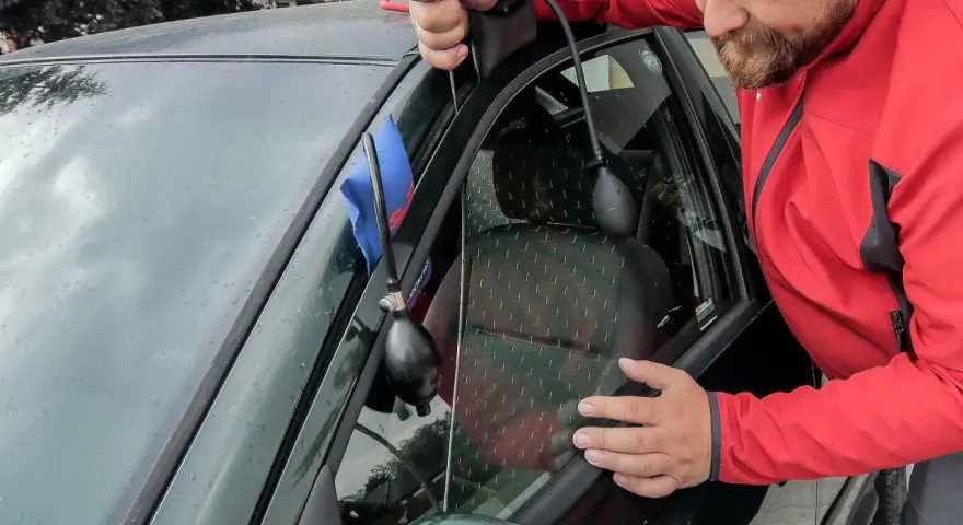 Mężczyzna używa narzędzi, aby otworzyć samochód z centralnym zamkiem. Wypompowuje powietrze, by stworzyć szczelinę.
