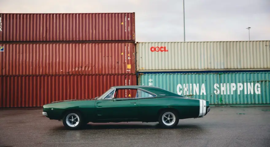 Klasyczne amerykańskie samochody, zielony Dodge Charger z lat 60. na tle kontenerów portowych.
