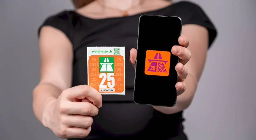 Kobieta trzyma w dłoniach winietę szwajcaria i smartfon z aplikacją.