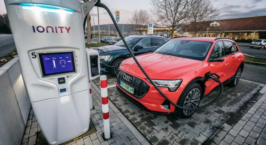 Na stacji Ionity czerwony Audi e-tron ładuje się. Ekran pokazuje 91% naładowania i 77kW mocy. Ile trwa ładowanie samochodu elektrycznego na stacji?