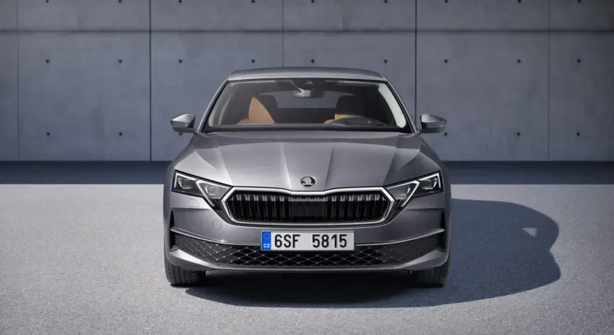Nowa Skoda Octavia w szarym kolorze, z brązowym wnętrzem, prezentuje się elegancko na tle betonowej ściany.