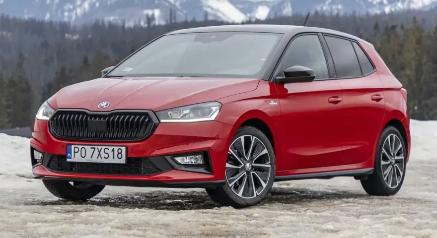 Czerwona Skoda Fabia Monte Carlo z czarnym dachem na tle ośnieżonych gór.