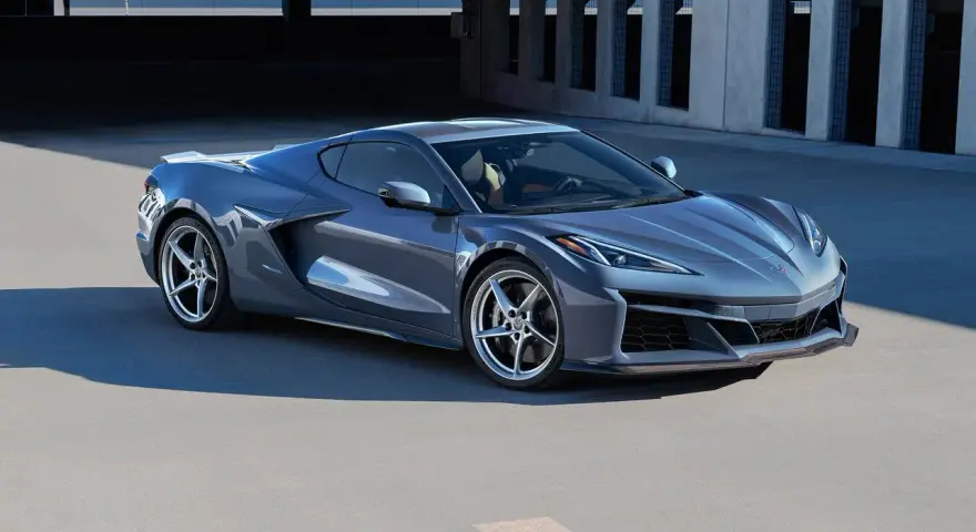 Szary Chevrolet Corvette Stingray z nowoczesnym designem, zaparkowany na tle betonowej architektury.