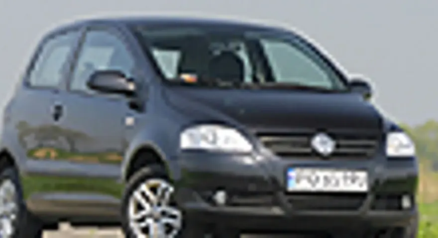 Czarny VW Fox z polskimi tablicami rejestracyjnymi stoi na tle zieleni.