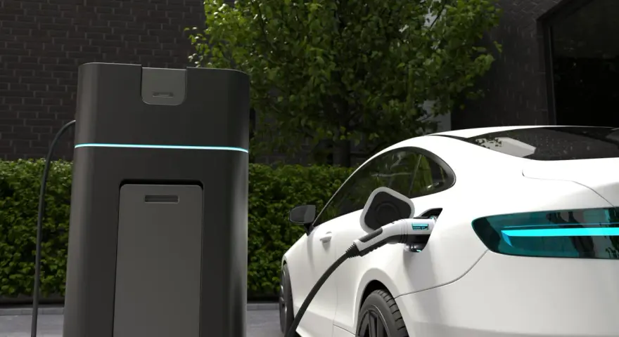 Biała Tesla ładuje się przy nowoczesnej stacji. Wyświetlacz pokazuje "CHARGING 100%", odpowiadając na pytanie, jak długo ładuje się Tesla.