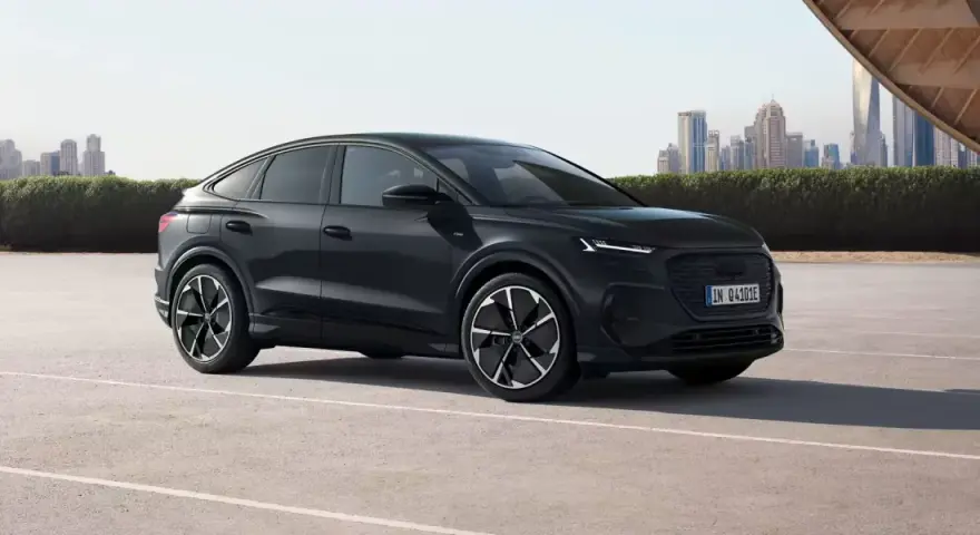 Elegancki, czarny Audi Q4 e-tron, elektryk z dynamiczną linią nadwozia, zaparkowany na tle nowoczesnej panoramy miasta.
