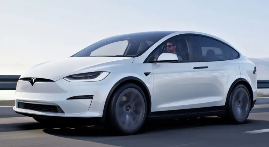 Biała Tesla Model X jedzie po drodze. Zastanawiasz się, ile kosztuje Tesla Model X?