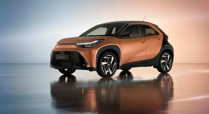 Pomarańczowa Toyota Aygo X z czarnymi dodatkami, idealna do miasta. Sprawdź atrakcyjną toyota hybryda cena.