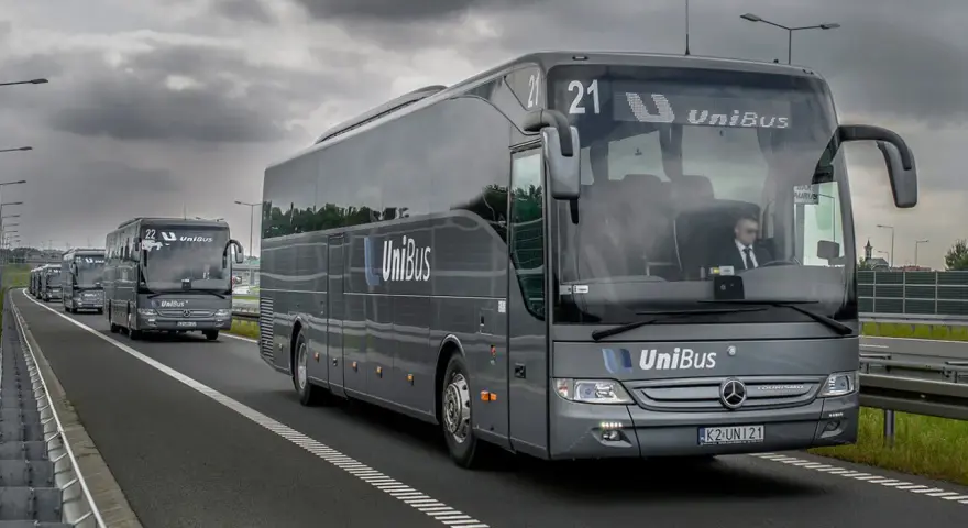 Szary bus UniBus z numerem 21 jedzie autostradą. To jeden z wielu pojazdów na trasie Kraków-Katowice.