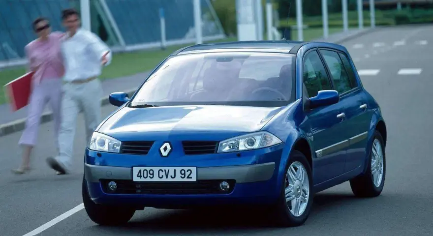Niebieski Renault Megane 2 na drodze, z parą ludzi w tle.