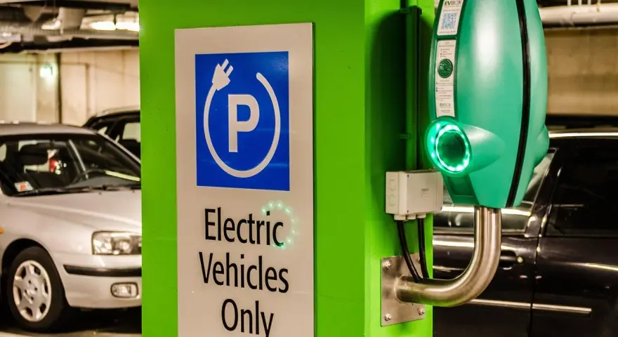 Znak "Tylko pojazdy elektryczne" i zielona ładowarka EVbox. Zastanawiasz się, ile kosztuje ładowanie samochodu elektrycznego w domu?
