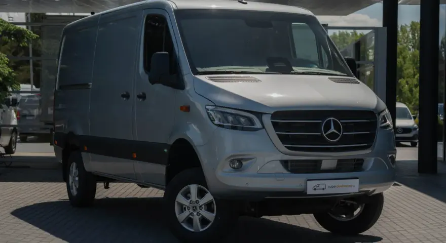 Srebrny bus Mercedes-Benz Sprinter, idealny jako jaki bus na budowę, stoi na parkingu przed nowoczesnym budynkiem.
