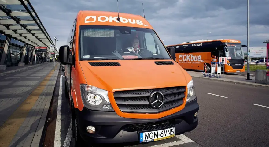 Pomarańczowy bus OKBUS czeka na pasażerów. Zastanawiasz się, ile kosztuje bus z Łodzi do Uniejowa? Sprawdź ofertę przewoźnika.