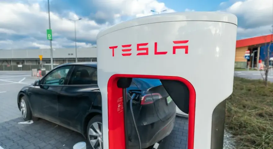 Czarna Tesla podłączona do ładowarki. Zastanawiasz się, ile kosztuje ładowanie Tesli? To zależy od taryfy i lokalizacji.