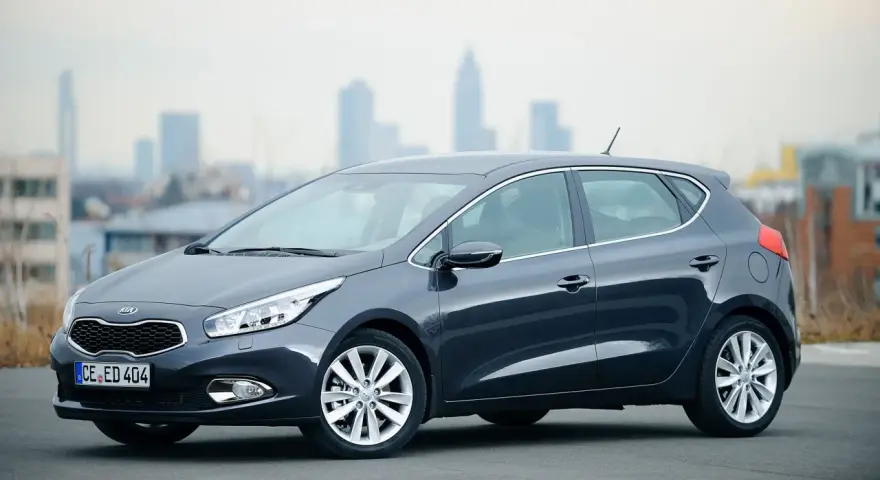 Ciemnoszary Kia Ceed 1. hatchback stoi na tle miejskiej panoramy.