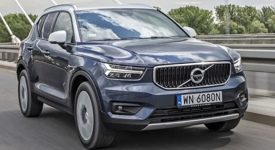 Ciemnogranatowy Volvo XC40 jedzie po moście. Sprawdź aktualną volvo xc40 cena i ofertę.