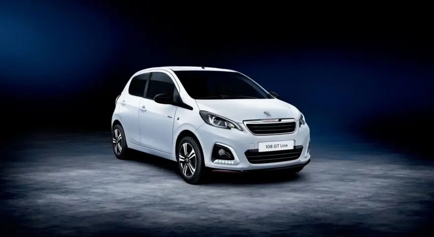 Biały Peugeot 108 GT Line stoi na ciemnym tle.